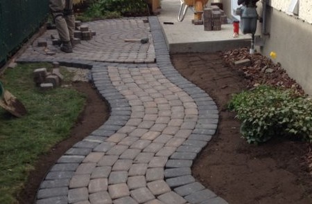 Build out a curving pathway of interlock unistone along side of a hosue