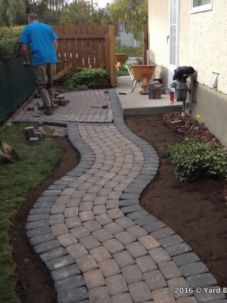 Build out a curving pathway of interlock unistone along side of a hosue